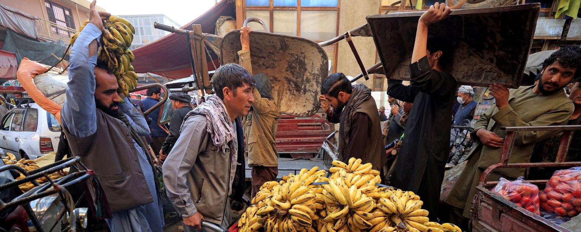 Мужчина толкает тачку с бананами на рынке в Кабуле - Sputnik Moldova-România, 1920, 02.11.2021