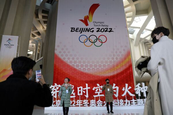 Oamenii pozează înainte de ceremonie, lângă bannerul dedicat Jocurilor Olimpice de iarnă de la Beijing 2022 - China, 20 octombrie 2021. - Sputnik Moldova