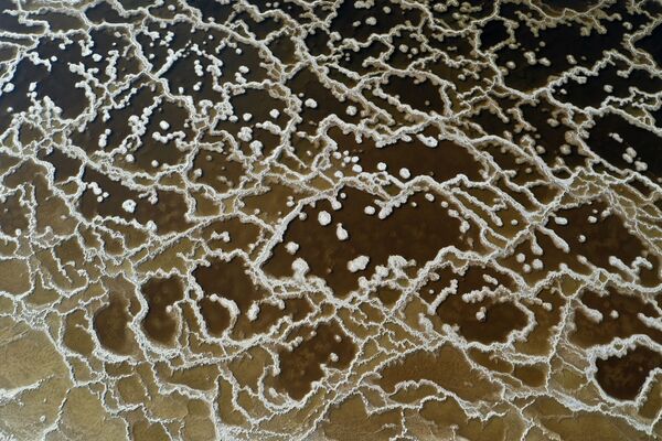 На снимке видны узоры, образованные кристаллизованными минералами на поверхности прудов-испарителей Мертвого моря, недалеко от южного израильского мошава Эйн-Тамар.  - Sputnik Молдова