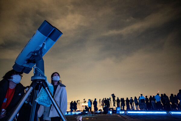 Oamenii exploarează cerul înstelat cu ajutorul unui telescop în timp ce fotografii și cameramanii imortalizează eclipsa de Lună, toate acestea fiind monitorizate  de pe puntea de observare a dealurilor Roppongi din Tokyo, 19 noiembrie 2021, Japonia. - Sputnik Moldova-România