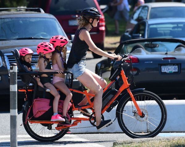 O femeie cu copii săi în timpul unei promenade cu bicicleta într-o zi fierbinte în orașul Vancouver, 29 iunie 2021. În acele zile, partea de vest a SUA, a fost cuprinsă de un val de arșiță fără precedent în istoria țării, fiind doborâte mai multe recorduri de temperatură. - Sputnik Moldova-România