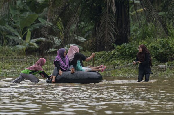 Locuitorii unei localități din Malaiezia sun nevoiți să se deplaseze cu o barcă pneumatică pe un drum scufundat în ape în urma inundațiilor  provocate de ploile musonice abundente, 7 ianuarie 2021. - Sputnik Moldova-România