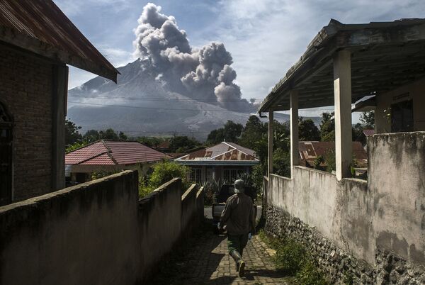 Un băștinaș dintr-un sat de la poalele Muntelui Sinabung din Sumatra de Nord, Indonezia. Pe 2 martie 2021, vulcanul Sinabung a aruncat o coloană de cenușă și nori de fum la o înălțime de aproximativ 5 kilometri. - Sputnik Moldova-România