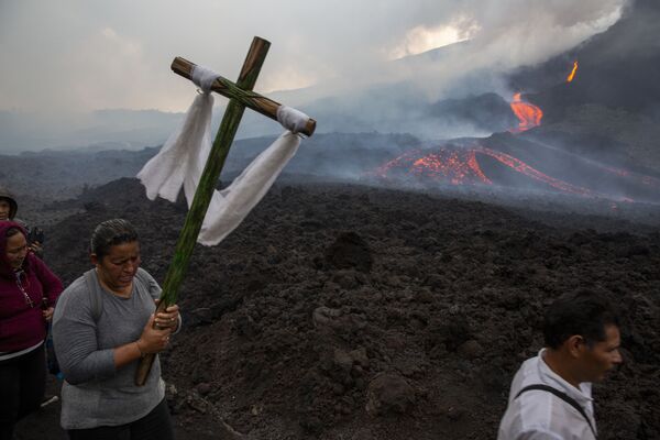 O femeie poartă o cruce în timpul unui pelerinaj pentru a se ruga ca vulcanul Pacaya să-și reducă din intensitate în San Vicente Pacaya, Guatemala, 5 mai 2021. Vulcanul, aflat chiar la sud de capitala țării, este activ de la începutul lunii februarie. - Sputnik Moldova-România