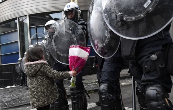 Девочка дарит цветы сотрудникам полиции во время акции протеста против мер по борьбе с коронавирусом в Брюсселе, Бельгия. - Sputnik Молдова