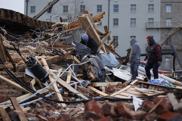 Oamenii caută printr-o clădire deteriorată de tornadă pe 11 decembrie 2021 în Mayfield, Kentucky. Mai multe tornade au străbătut părți din Vestul Mijlociu de jos vineri noaptea târziu, lăsând o cale mare de distrugere și decese necunoscute. - Sputnik Moldova-România