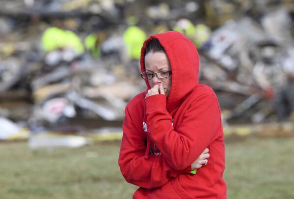 O femeie se îndepărtează de ceea ce a mai rămas dintr-o fabrică de produse de consum din Mayfield, după distrugerile provocate de o tornadăîn statul american Kentucky, pe 11 decembrie 2021.  - Sputnik Moldova-România