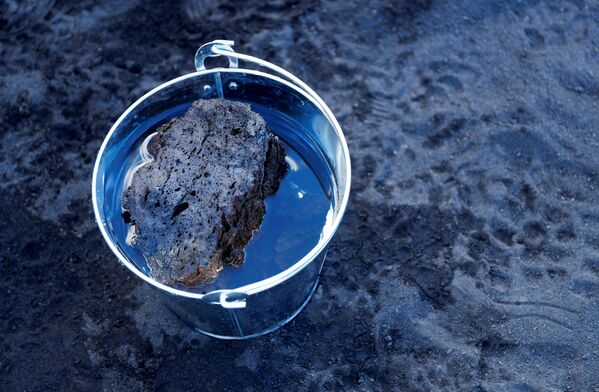 Камень, выброшенный вулканом Кумбре Вьеха недалеко от района Таканде, охлаждается в воде для исследования. - Sputnik Молдова