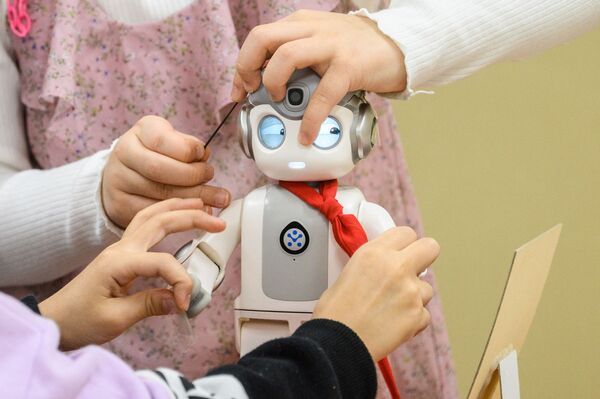 Дети играют с 24-сантиметровым роботом &quot;Альфа Мини&quot;, который умеет петь, танцевать и даже учить кунг-фу. В школе Мару в Сеуле начали использовать роботов-малышей в качестве помощников в детском саду. - Sputnik Молдова