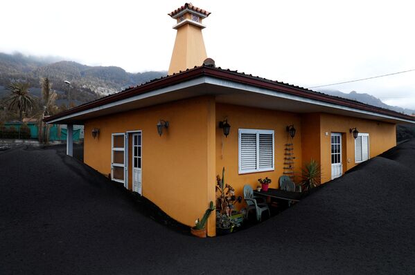 O casă înconjurată de cenușă de la vulcanul Cumbre Vieja este văzută într-un cartier din Las Manchas, pe insula Canare La Palma, Spania, 16 decembrie 2021. - Sputnik Moldova-România