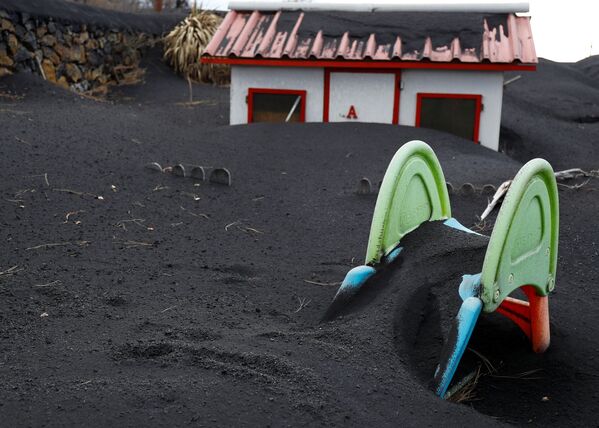 Un tobogan îngropat în cenușa vulcanului Cumbre Vieja în grădina unei case, într-un cartier din Las Manchas, pe insula Canare La Palma, Spania, 16 decembrie 2021. - Sputnik Moldova-România