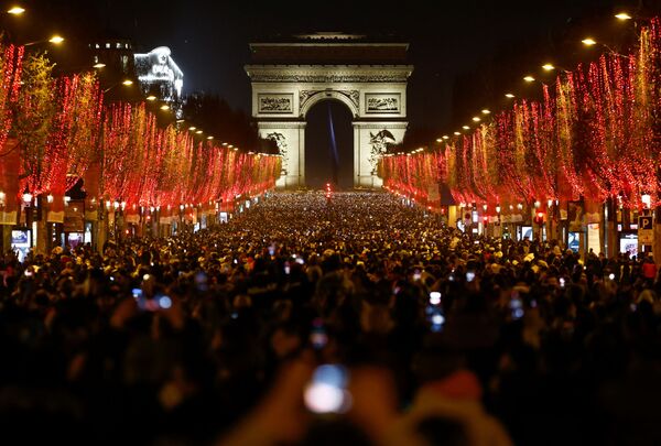 Oamenii participă la sărbătorile de Anul Nou pe bulevardul Champs-Elysees, deoarece spectacolul tradițional de lumini și artificiile au fost anulate din cauza răspândirii bolii coronavirus (COVID-19) în Paris, Franța, 31 decembrie 2021. - Sputnik Moldova-România
