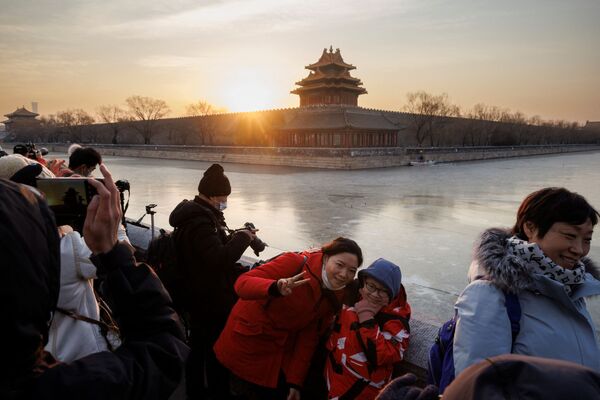 Oamenii pozează în timpul primului răsărit de soare al anului deasupra Orașului Interzis din Beijing, în timp ce orașul se pregătește să găzduiască Jocurile Olimpice de iarnă, la Beijing, China, 1 ianuarie 2022. - Sputnik Moldova-România