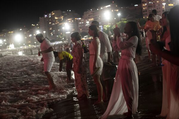 Petrecăreții salută Anul Nou în timp ce privesc artificiile explodând peste plaja Copacabana, din Rio de Janeiro, Brazilia, sâmbătă, 1 ianuarie 2022. - Sputnik Moldova-România