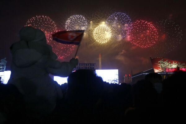 Oameni ce urmăresc artificiile care sărbătoresc Anul Nou în Piața Kim Il Sung din Phenian, Coreea de Nord, sâmbătă, 1 ianuarie 2022. - Sputnik Moldova-România