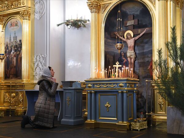 O femeie credincioasă rugându-se Mâtuitorului înainte de începerea slujbei din Ajunul de Crăciun în Catedrala Icoana Maicii Domnului din Kazan. - Sputnik Moldova-România