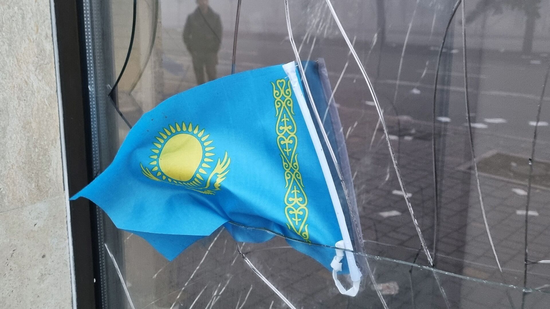 Государственный флаг Казахстана виден в разбитом окне отделения Kaspi Bank после протестов, вызванных повышением цен на топливо в Алматы - Sputnik Moldova, 1920, 08.01.2022