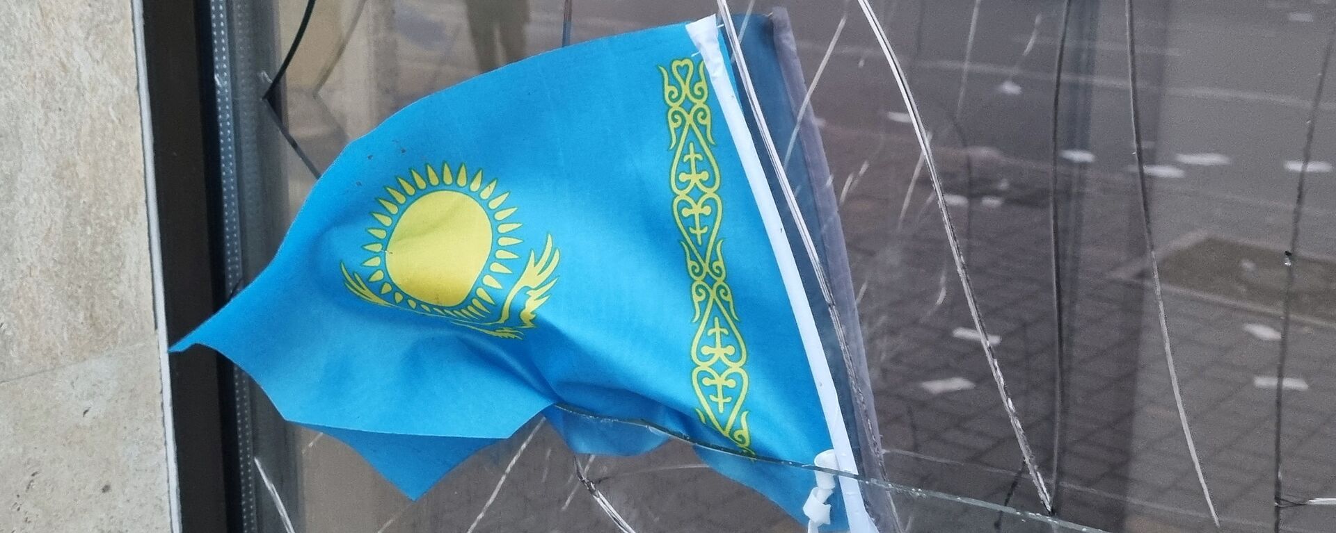 Государственный флаг Казахстана виден в разбитом окне отделения Kaspi Bank после протестов, вызванных повышением цен на топливо в Алматы - Sputnik Moldova, 1920, 08.01.2022