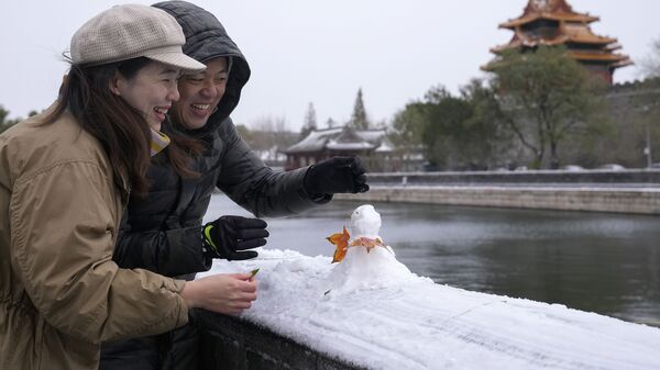 Китайская пара лепит снеговика возле Запретного города в Пекине - Sputnik Молдова