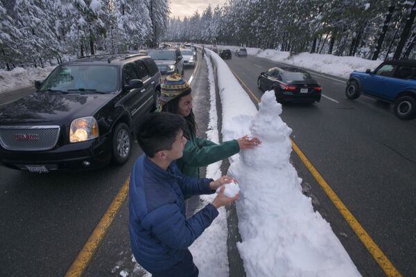 Молодые люди лепят снеговика на шоссе в Калифорнии, США. - Sputnik Молдова