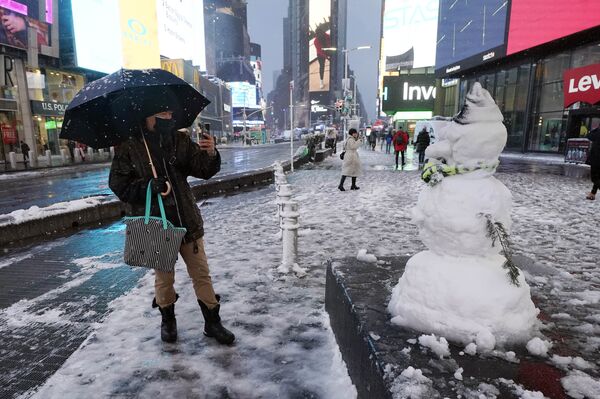 Мужчина фотографирует снеговика на Таймс-сквер в Нью-Йорке, США. - Sputnik Молдова