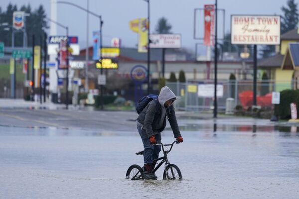 Велосипедист пытается пересечь залитую водой улицу. - Sputnik Молдова