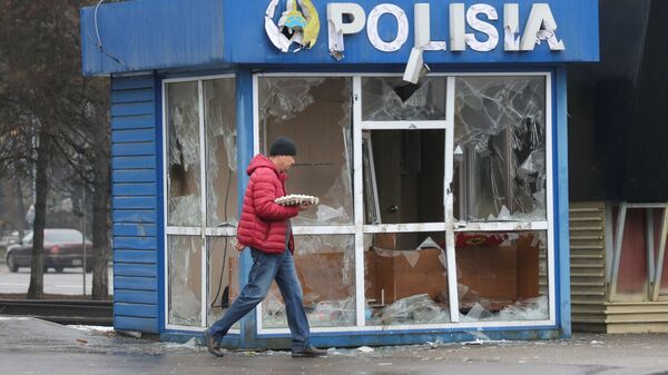 Мужчина проходит мимо полицейского участка, разрушенного во время беспорядков в Алматы - Sputnik Moldova