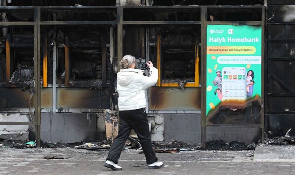 Женщина снимает здание, сожженное во время массовых протестов. - Sputnik Молдова