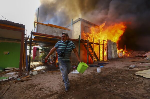 Мужчина у горящего дома в чилийском городе Икике. - Sputnik Молдова