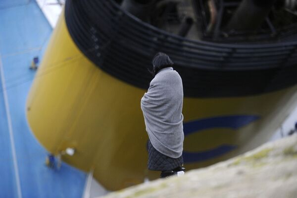 Женщина смотрит на частично затопленный круизный лайнер Costa Concordia. - Sputnik Молдова