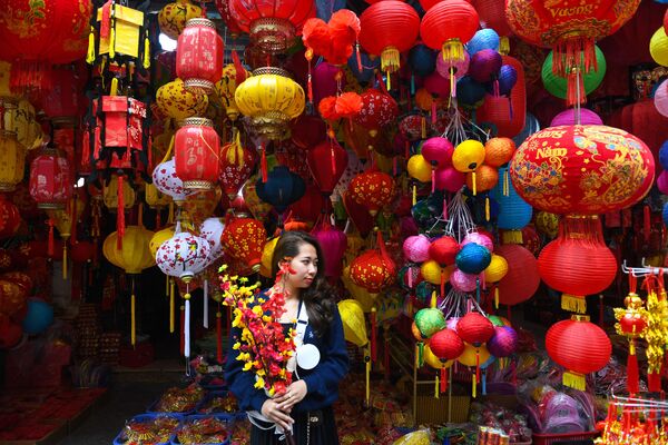 Un comerciant pozează în fața unui magazin care vinde decorațiuni în cartierul vechi din Hanoi, pe 11 ianuarie 2022, înainte de Anul Nou Lunar sau sărbătoarea Tet. - Sputnik Moldova-România