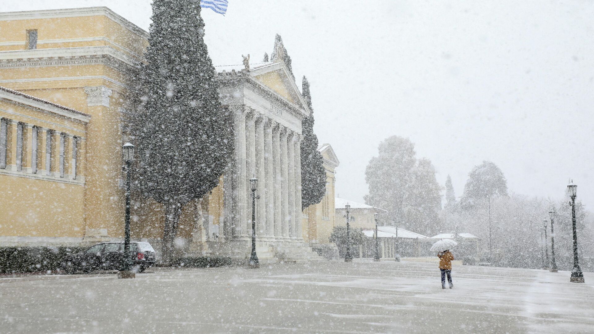 Женщина с зонтиком проходит мимо зала Заппейон во время сильного снегопада в Афинах, Греция, 24 января 2022 года. - Sputnik Молдова, 1920, 24.01.2022