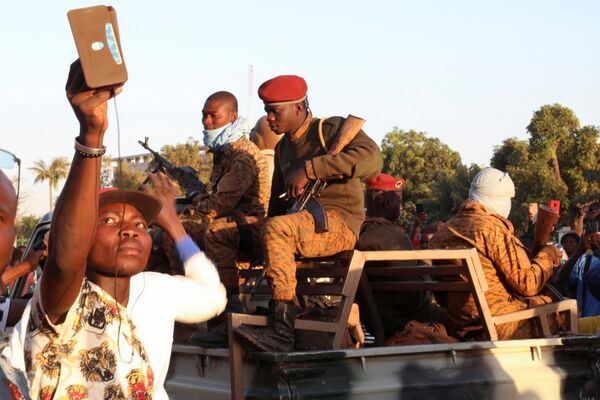 Un bărbat își folosește telefonul mobil lângă soldații armatei după ce l-au detronat pe președintele Kabore în Ouagadougou, Burkina Faso, 24 ianuarie 2022. - Sputnik Moldova-România