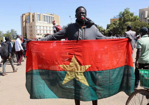 Un bărbat ține steagul național pentru a arăta sprijinul armatei după ce președintele Burkina Faso, Roch Kabore, a fost reținut într-o tabără militară din Ouagadougou, Burkina Faso, 24 ianuarie 2022. - Sputnik Moldova-România