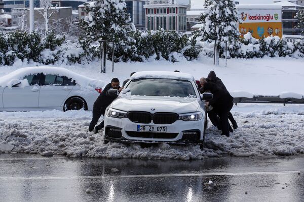 Oamenii împing o mașină pe o stradă acoperită de zăpadă din Istanbul, marți, 25 ianuarie 2022.  - Sputnik Moldova-România