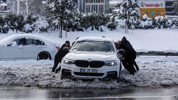 Люди толкают машину на заснеженной улице в Стамбуле - Sputnik Moldova-România