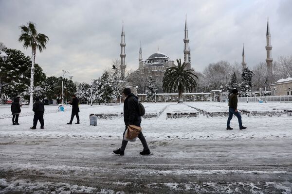 Oamenii se plimbă în preajma Moscheei Sultanahmet, cunoscută sub numele de Moscheea Albastră, în fundal, în timpul ninsorilor abundente din Istanbul, Turcia, 25 ianuarie 2022. - Sputnik Moldova-România