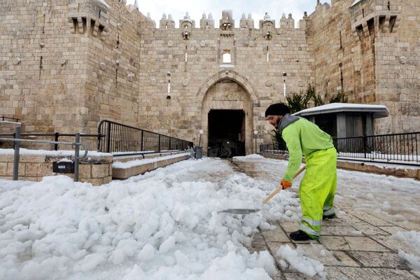 Мужчина сгребает снег перед Дамасскими воротами в Старом городе Иерусалима. - Sputnik Молдова