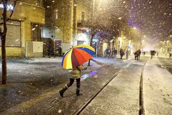 Человек идет с зонтиком во время снежной бури в Иерусалиме. - Sputnik Молдова