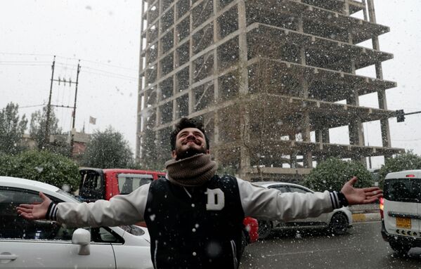 Un bărbat se bucură de zăpadă pe o stradă din orașul Erbil, Irak. Imaginea a fost surprinsă pe 20 ianuarie 2022. - Sputnik Moldova