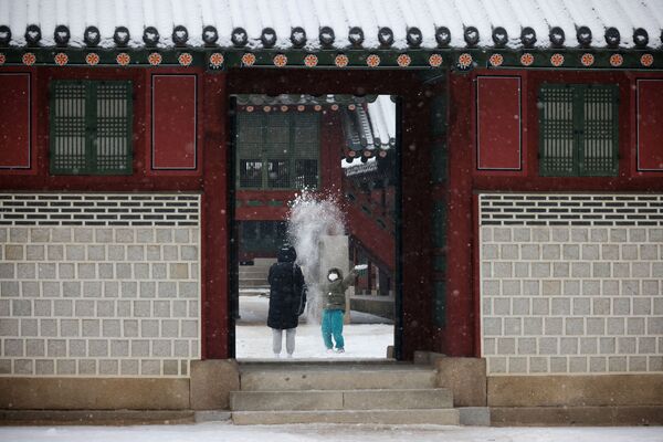 Un copil se bucură și se joacă cu zăpada la Palatul Deoksu din Seul. Imaginea a fost surprinsă pe 19 ianuarie în  Coreea de Sud. - Sputnik Moldova