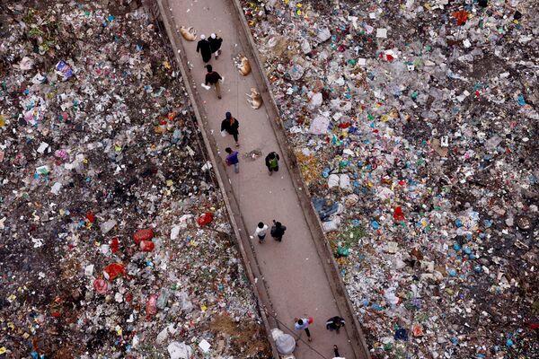 Пешеходы идут по мосту на фоне окружающего мусора в Дакке, Бангладеш. - Sputnik Молдова