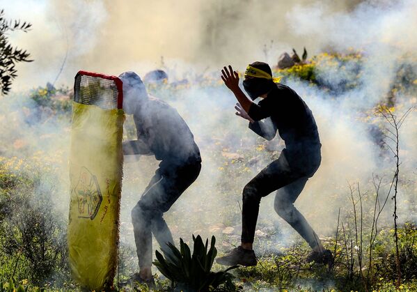 Палестинская молодежь прячется за импровизированным щитом во время столкновений с израильскими силами безопасности. - Sputnik Молдова