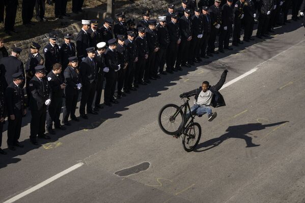 Человек едет на велосипеде по маршруту похоронной процессии после панихиды по трем погибшим пожарным в Балтиморе, штат Мэриленд. - Sputnik Молдова