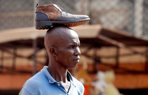 Мужчина с ботинком на голове на рынке Mvog Ada в Яунде, столице Камеруна. - Sputnik Молдова