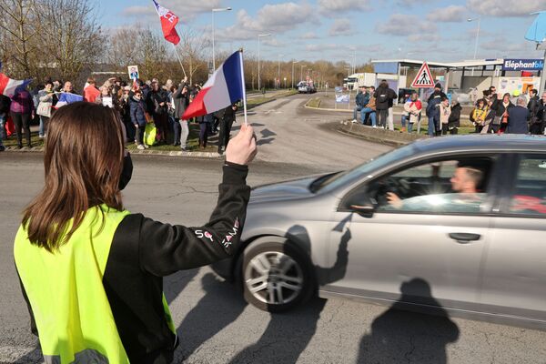 Susținătorii și membrii mișcării vestelor galbene țin steagul național francez pe o parcare a unui centru comercial din Longueau, în timp ce aplaudă șoferii francezi privind restricțiile anti-COVID în timpul lor „Convoi de la liberte” (Convoiul Libertății), un protest de convoi de vehicule. convergând la Paris pentru a protesta împotriva vaccinului împotriva coronavirusului (COVID-19) și a restricțiilor din Franța, 11 februarie 2022. - Sputnik Moldova-România