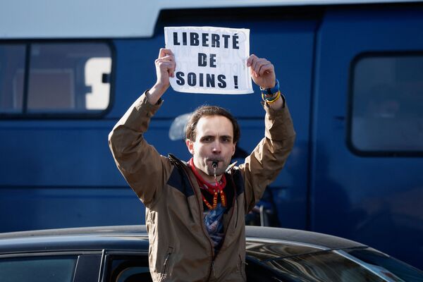 Un demonstrant ține un panou cu „Libertatea de îngrijire” pe bulevardul Champs-Elysees, în timp ce mașinile defilează în timpul „Convoi de la liberte” (Convoiul Libertății), un convoi de vehicule pentru a protesta împotriva vaccinului împotriva coronavirusului (COVID-19) și a restricțiilor în Paris, Franța, 12 februarie 2022. - Sputnik Moldova-România