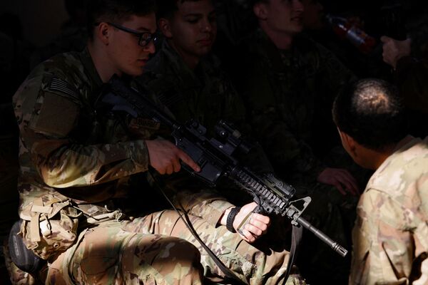 Un soldat din Divizia 82 Aeropurtată a Armatei SUA își verifică arma în timp ce așteaptă să se îmbarce într-un avion de transport cu destinația Europa, la Fort Bragg, Carolina de Nord, SUA, 14 februarie 2022. - Sputnik Moldova-România