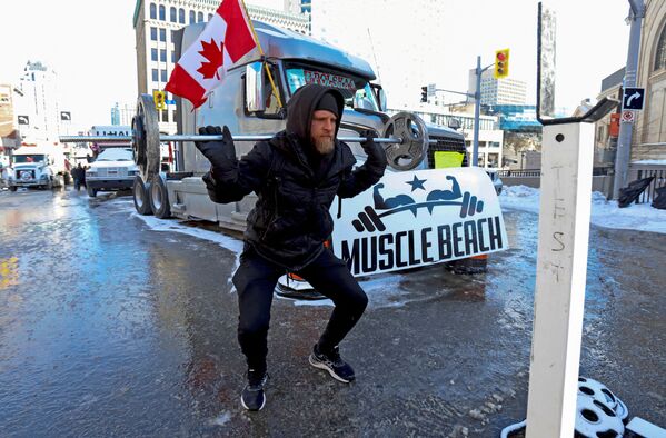 O persoană ridică greutăți în fața unui camion în timp ce camionerii și susținătorii lor continuă să protesteze împotriva vaccinării obligatorii în Ottawa, Ontario, Canada, 15 februarie 2022. - Sputnik Moldova-România