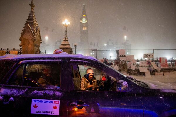 Человек в припаркованном автомобиле возле парламента Канады. На машине надпись: &quot;Конвой свободы-2022&quot;. - Sputnik Молдова